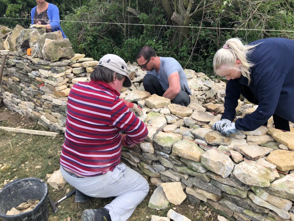 Hands building a dry stone wall during an Introduction to Dry Stone Walling workshop