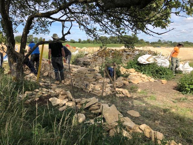 Close-up of hands selecting and placing stone during a dry stone walling workshop