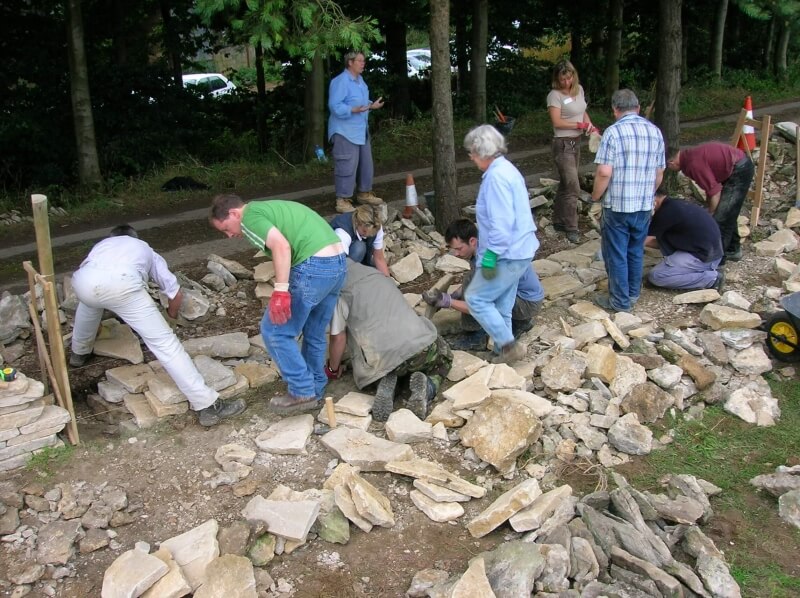 Small group of students building a dry stone wall together during a workshop