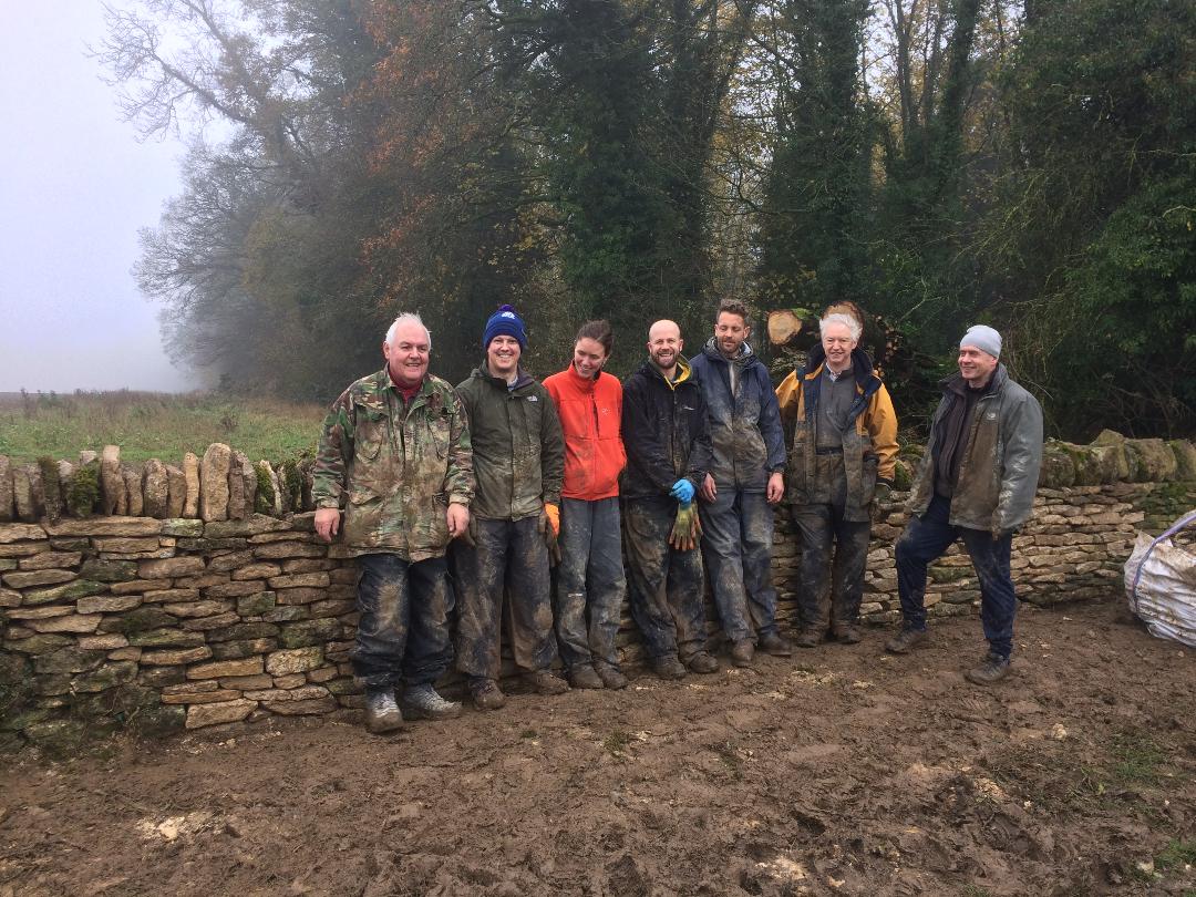 Small group of workshop participants smiling together after completing a dry stone wall